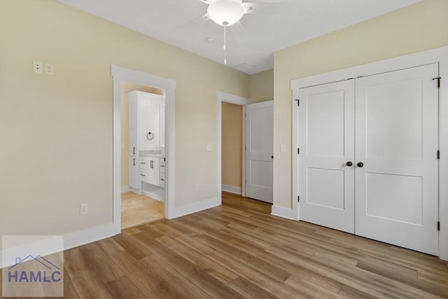 unfurnished bedroom with baseboards, wood finished floors, a closet, ceiling fan, and connected bathroom