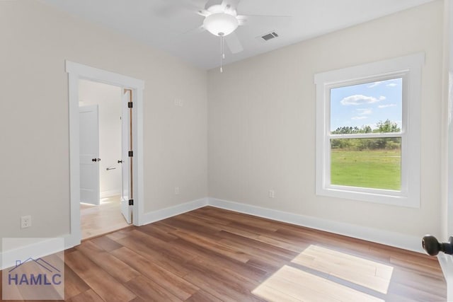 unfurnished room with baseboards, wood finished floors, visible vents, and ceiling fan