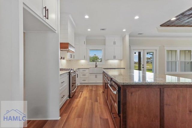 kitchen with visible vents, ornamental molding, a sink, stainless steel range with gas cooktop, and a wealth of natural light