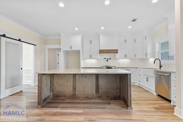 kitchen featuring a barn door, stainless steel dishwasher, ornamental molding, and custom range hood