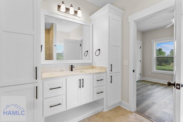 bathroom featuring baseboards, a healthy amount of sunlight, a ceiling fan, and vanity