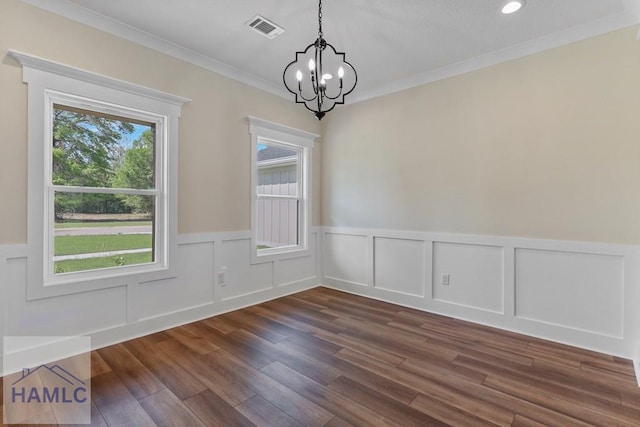 unfurnished dining area with a notable chandelier, crown molding, a wainscoted wall, dark wood-style flooring, and visible vents
