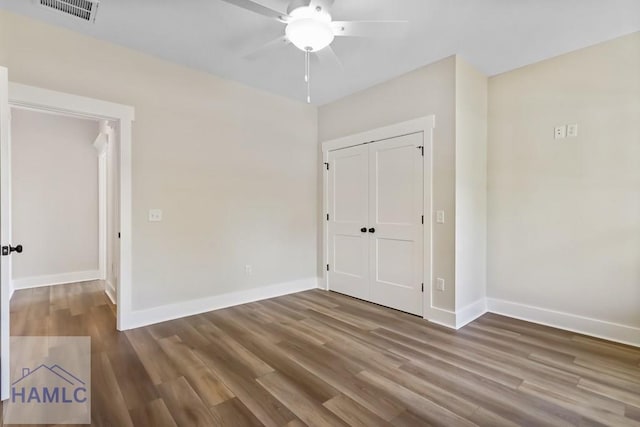 spare room with baseboards, wood finished floors, and visible vents