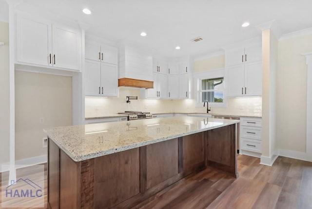 kitchen featuring white cabinets, a sink, baseboards, decorative backsplash, and custom range hood