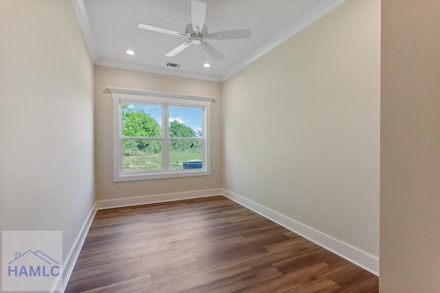 empty room with dark wood-style flooring, crown molding, and baseboards