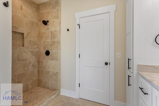 full bath featuring a tile shower and vanity