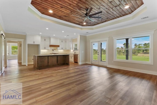 unfurnished living room featuring baseboards, ornamental molding, and a tray ceiling