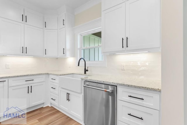 kitchen with white cabinets, stainless steel dishwasher, a sink, and tasteful backsplash