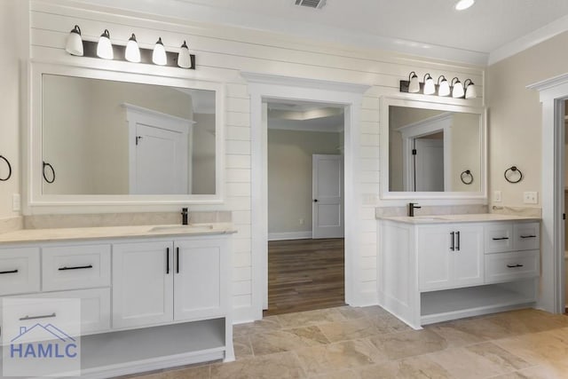 full bath with stone finish flooring, two vanities, visible vents, and a sink