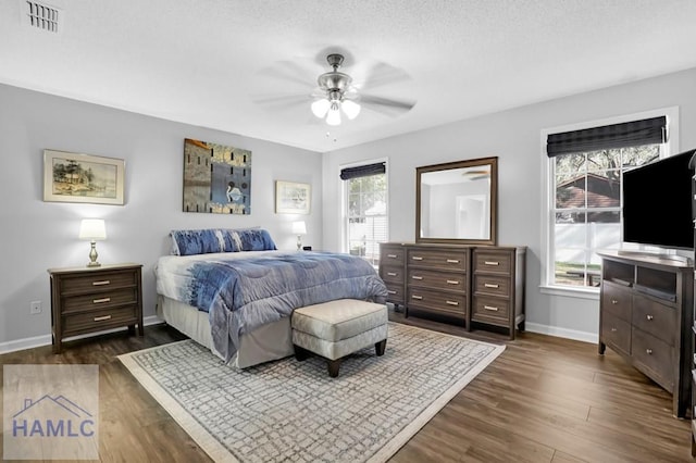 bedroom featuring ceiling fan, dark wood-type flooring, and a textured ceiling