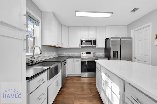 kitchen featuring appliances with stainless steel finishes, dark hardwood / wood-style floors, white cabinetry, and sink