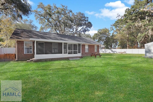 rear view of property featuring a sunroom and a yard