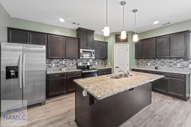 91 Thomas Way SE, Ludowici, GA 31316 - kitchen with stainless steel appliances, light wood-style floors, decorative backsplash, dark brown cabinets, and a textured ceiling