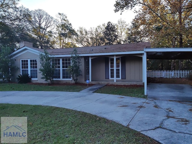 ranch-style home featuring a porch, a front yard, and a carport