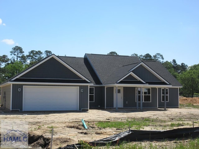 view of front of property with an attached garage, a porch, and roof with shingles