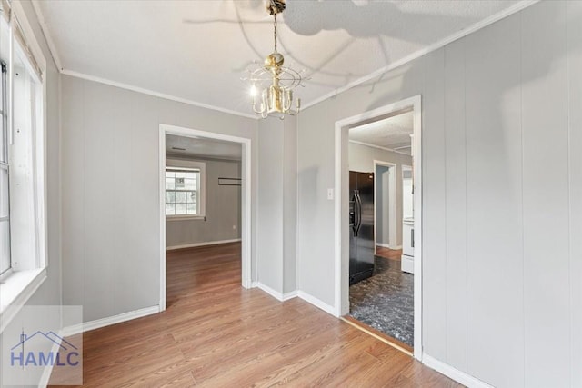 spare room with ornamental molding, a chandelier, and light wood-type flooring