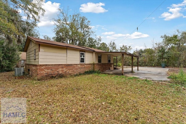 rear view of property with a yard, a carport, and central air condition unit