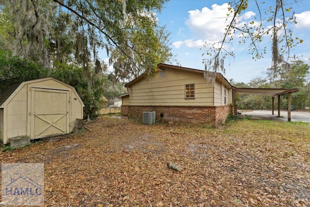 view of side of home featuring cooling unit, a carport, and a storage shed