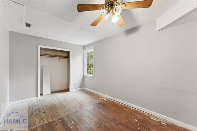 unfurnished bedroom with wood-type flooring, a textured ceiling, a closet, and ceiling fan