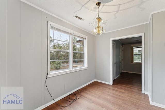 spare room with crown molding, wood-type flooring, a chandelier, and a textured ceiling