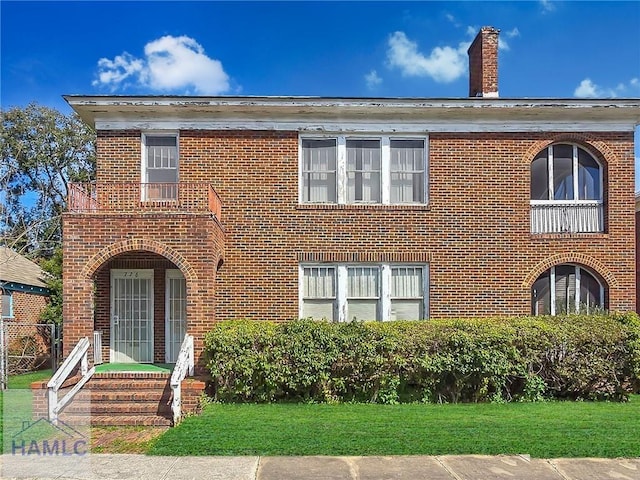 view of front of home with brick siding, a chimney, and a front yard