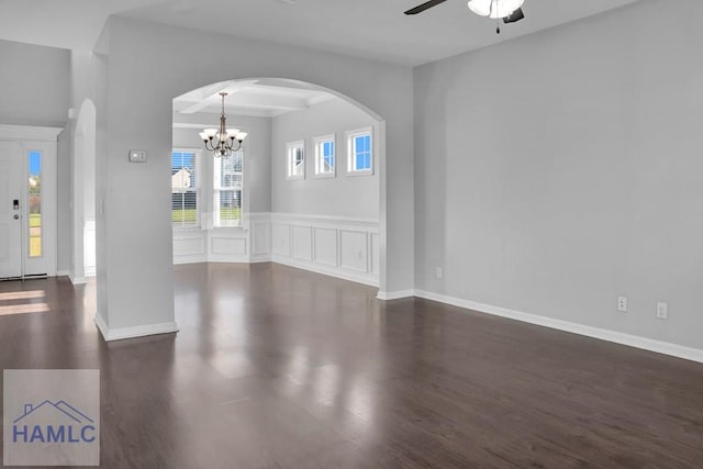 spare room featuring dark wood-type flooring and ceiling fan with notable chandelier