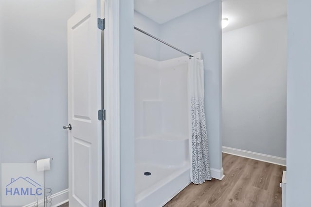 full bathroom with curtained shower, baseboards, and wood finished floors