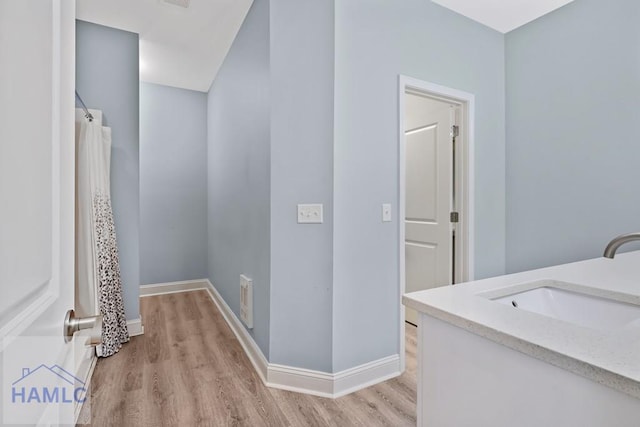 laundry room with visible vents, baseboards, light wood-type flooring, and a sink