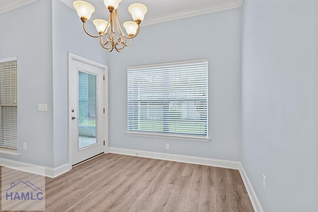 unfurnished dining area featuring baseboards, a notable chandelier, wood finished floors, and crown molding