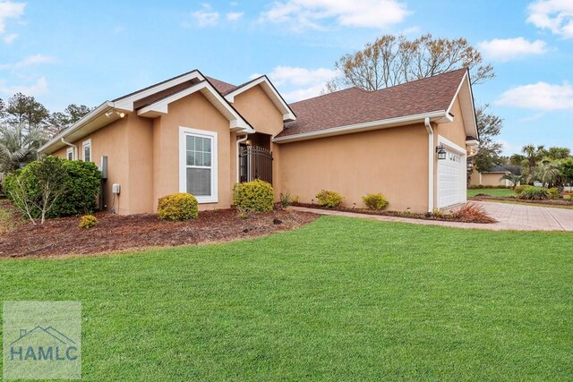 ranch-style home featuring stucco siding, a front lawn, a gate, decorative driveway, and a garage