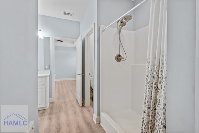 bathroom featuring vanity, wood finished floors, visible vents, a stall shower, and toilet