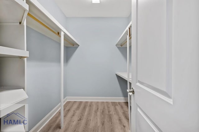 walk in closet with wood finished floors