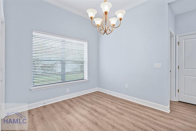 spare room with crown molding, light wood-style floors, baseboards, and a chandelier