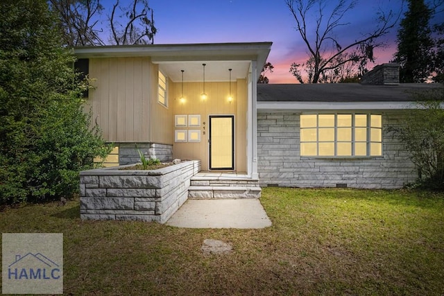 property entrance with a lawn, a chimney, and crawl space