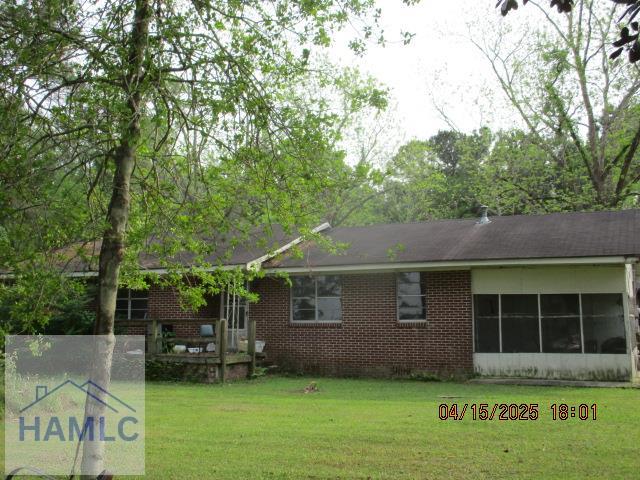 rear view of property with a lawn and brick siding