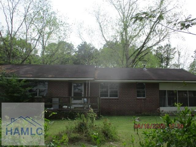 rear view of property with a lawn and brick siding