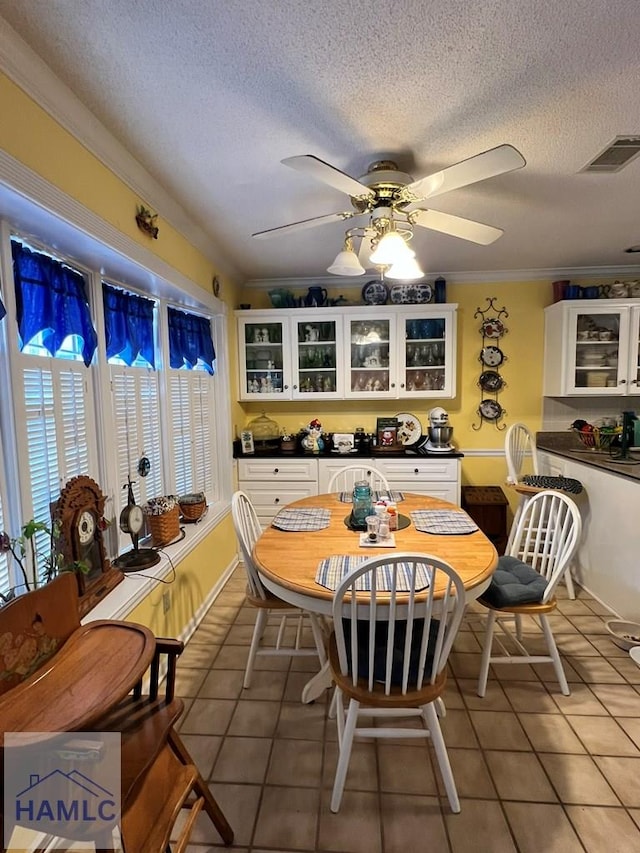 tiled dining space with crown molding, ceiling fan, and a textured ceiling