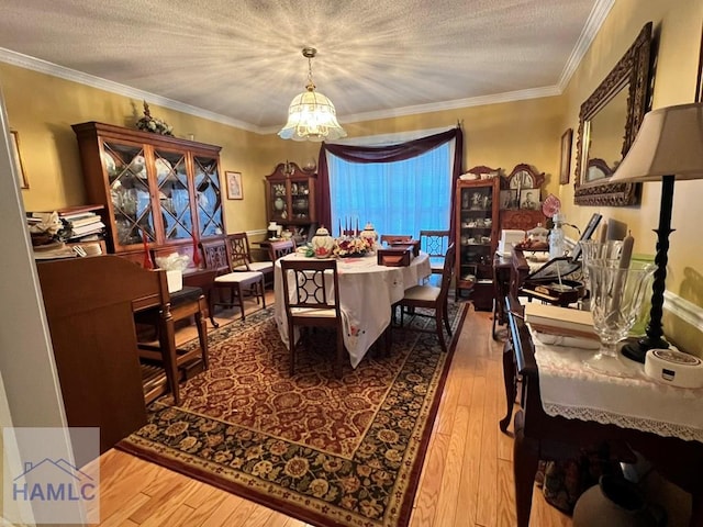 dining room featuring a chandelier, wood-type flooring, a textured ceiling, and ornamental molding