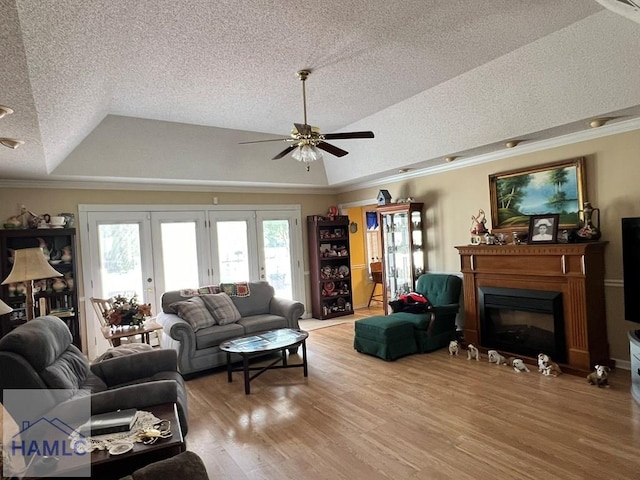 living room with ceiling fan, french doors, a raised ceiling, light wood-type flooring, and ornamental molding