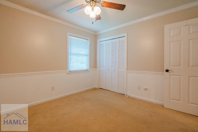 unfurnished bedroom with baseboards, ornamental molding, carpet floors, and a closet