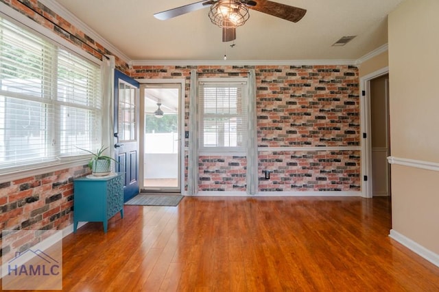 interior space featuring visible vents, ceiling fan, wood finished floors, and brick wall