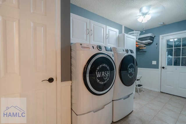 laundry room with a textured ceiling, cabinet space, and washer and clothes dryer