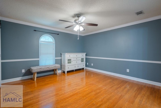 bedroom featuring a textured ceiling, crown molding, visible vents, baseboards, and light wood finished floors