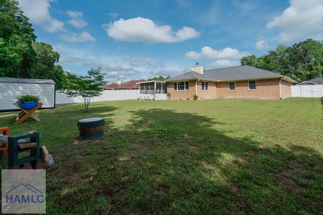 view of yard with a fenced backyard, an outbuilding, a sunroom, and a storage shed