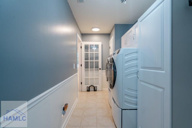laundry area with light tile patterned floors, washer and dryer, and cabinet space