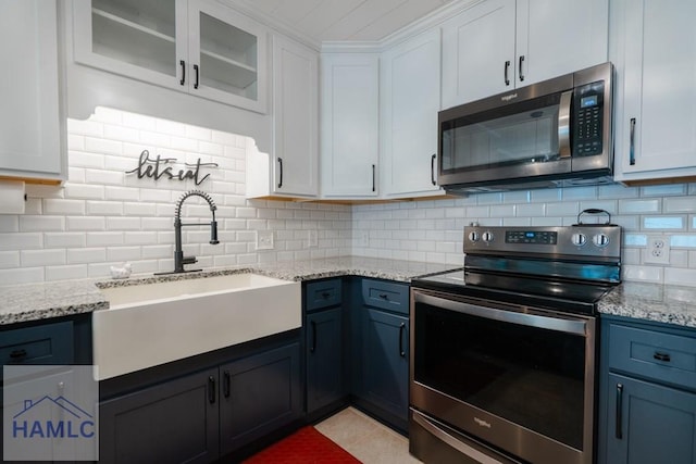 kitchen with white cabinets, stainless steel appliances, decorative backsplash, and a sink