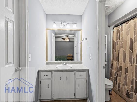 bathroom featuring ceiling fan, vanity, toilet, and a textured ceiling