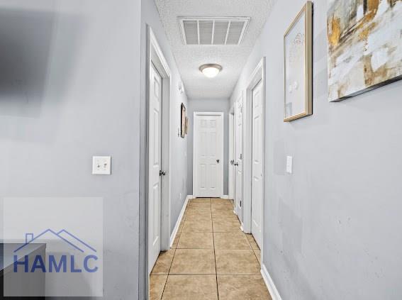 hallway featuring a textured ceiling and light tile patterned floors