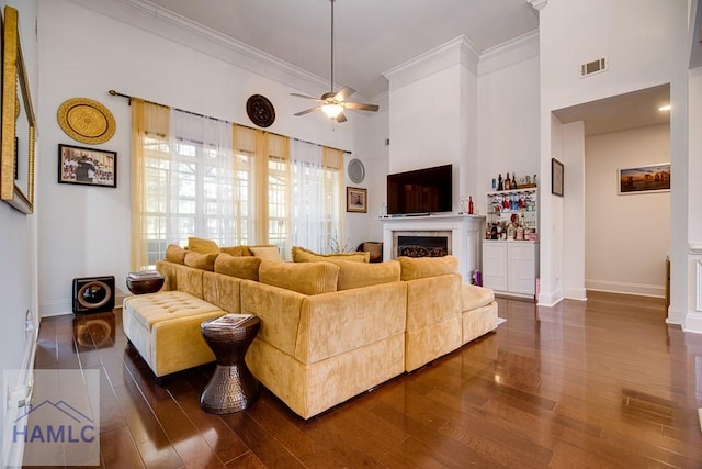 living room with ceiling fan, dark hardwood / wood-style floors, ornamental molding, and a high ceiling