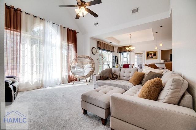 living room featuring carpet, ceiling fan with notable chandelier, a towering ceiling, and a tray ceiling